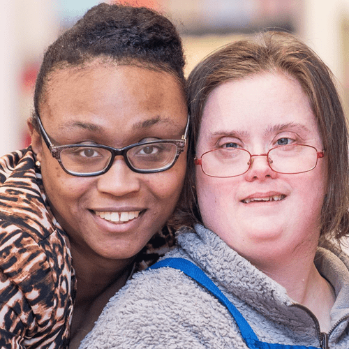 Two smiling women, posing closely together.